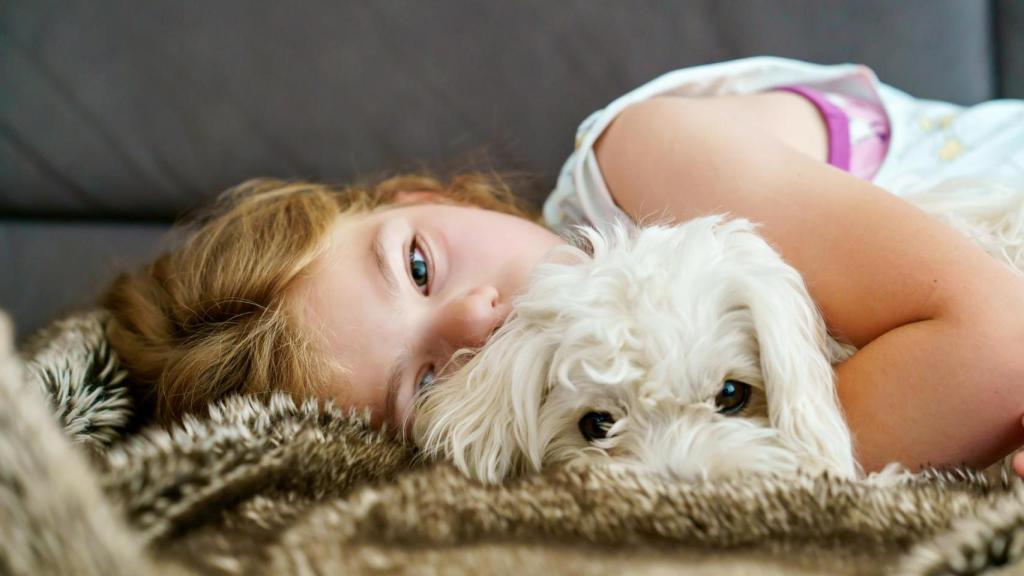 Una niña abrazada a un perro.
