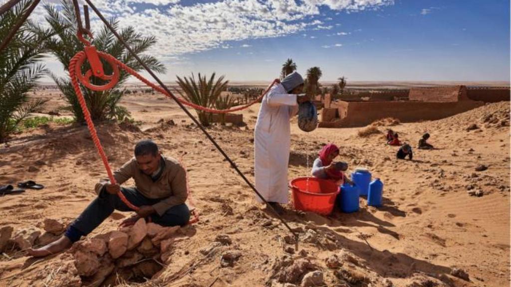 Extracción de agua de un pozo tradicional mediante un sistema manual de poleas.