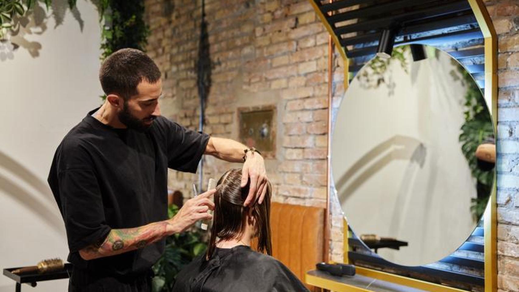 Peluquero cortando el pelo a su clienta.
