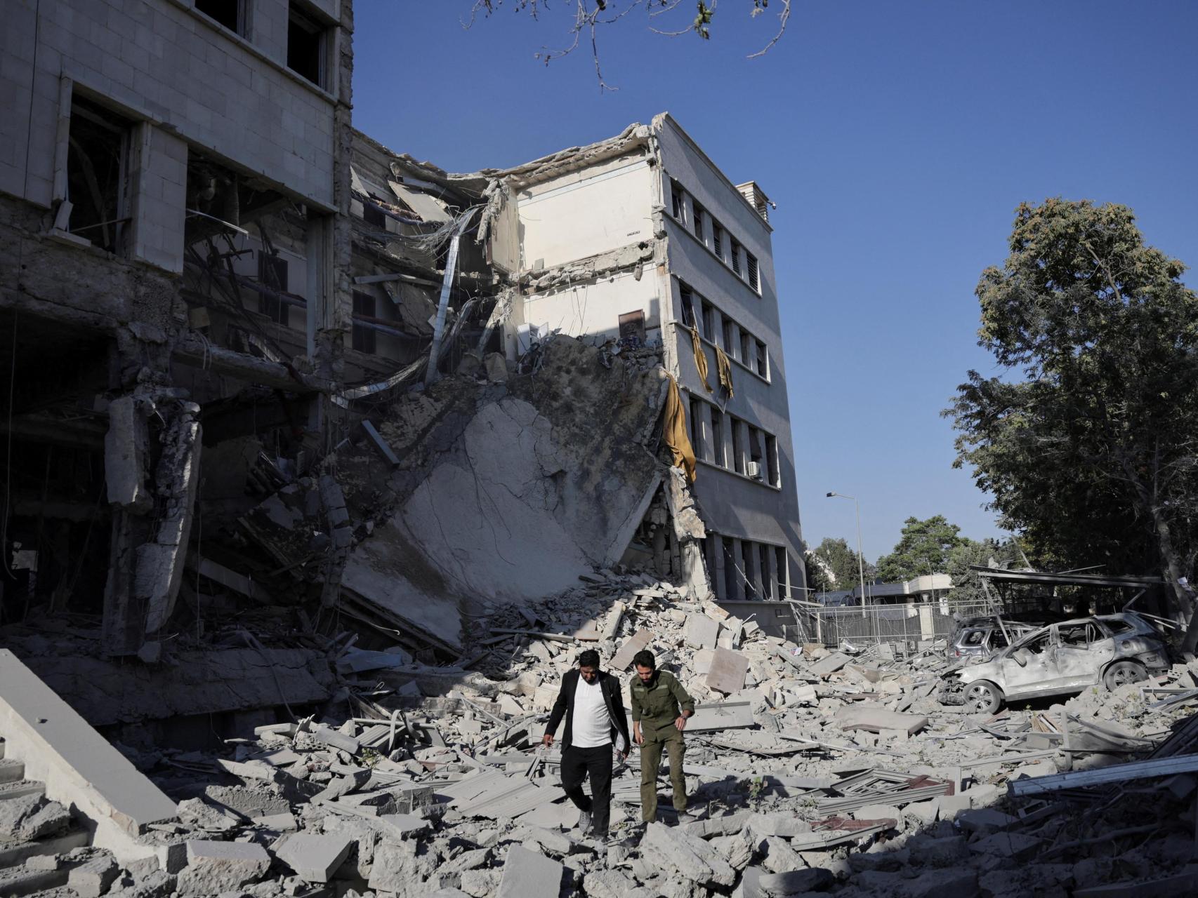 Hombres caminan entre los escombros, después de potentes ataques aéreos sacudieron Damasco el miércoles, dirigido al Ministerio de Defensa, como Israel prometió destruir las fuerzas del gobierno sirio que atacan a las comunidades drusas en el sur de Siria y exigió su retirada, en Damasco 16 de julio 2025.