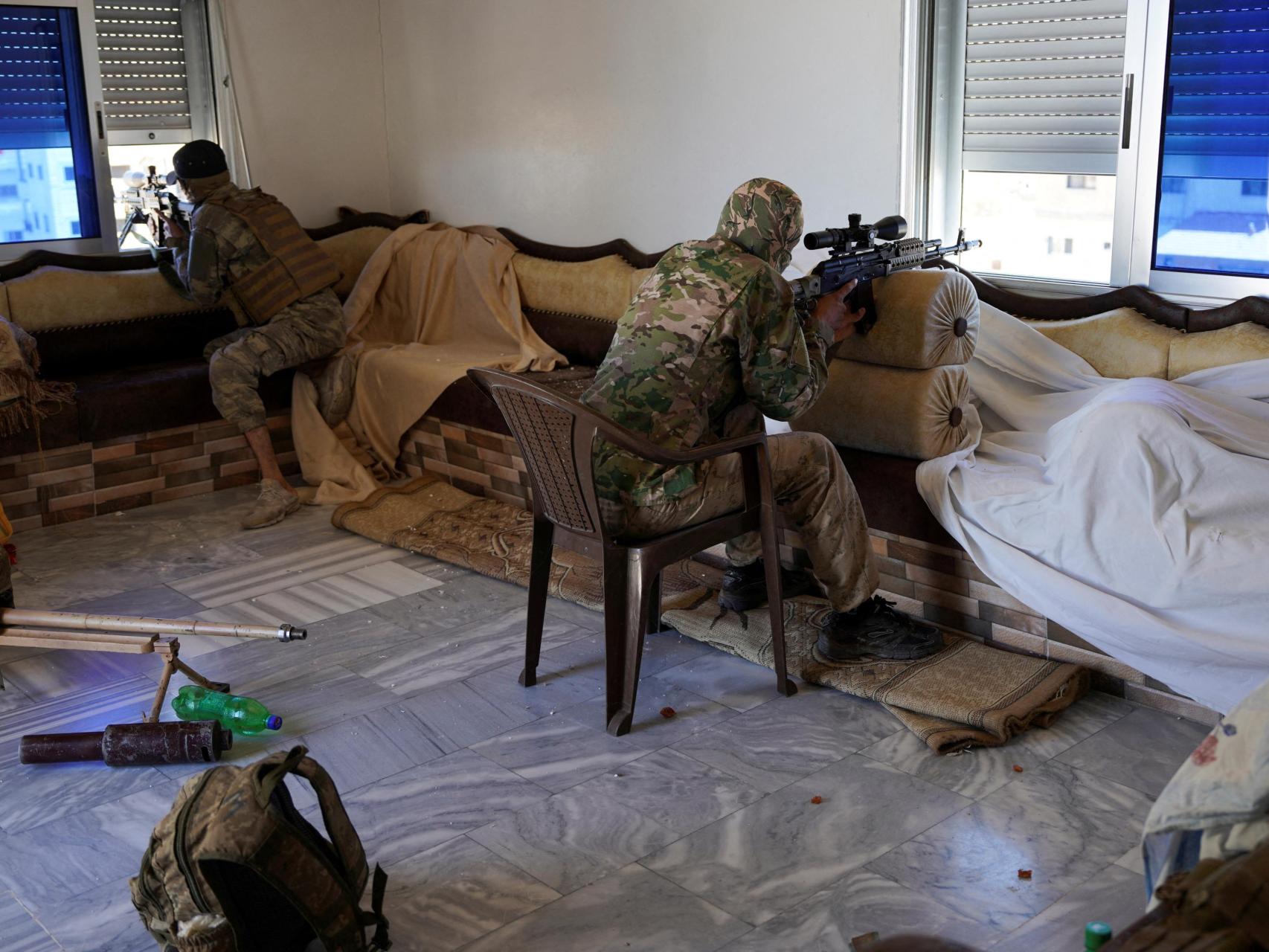 Miembros de las fuerzas de seguridad sirias toman posición dentro de una casa, en Sueida.