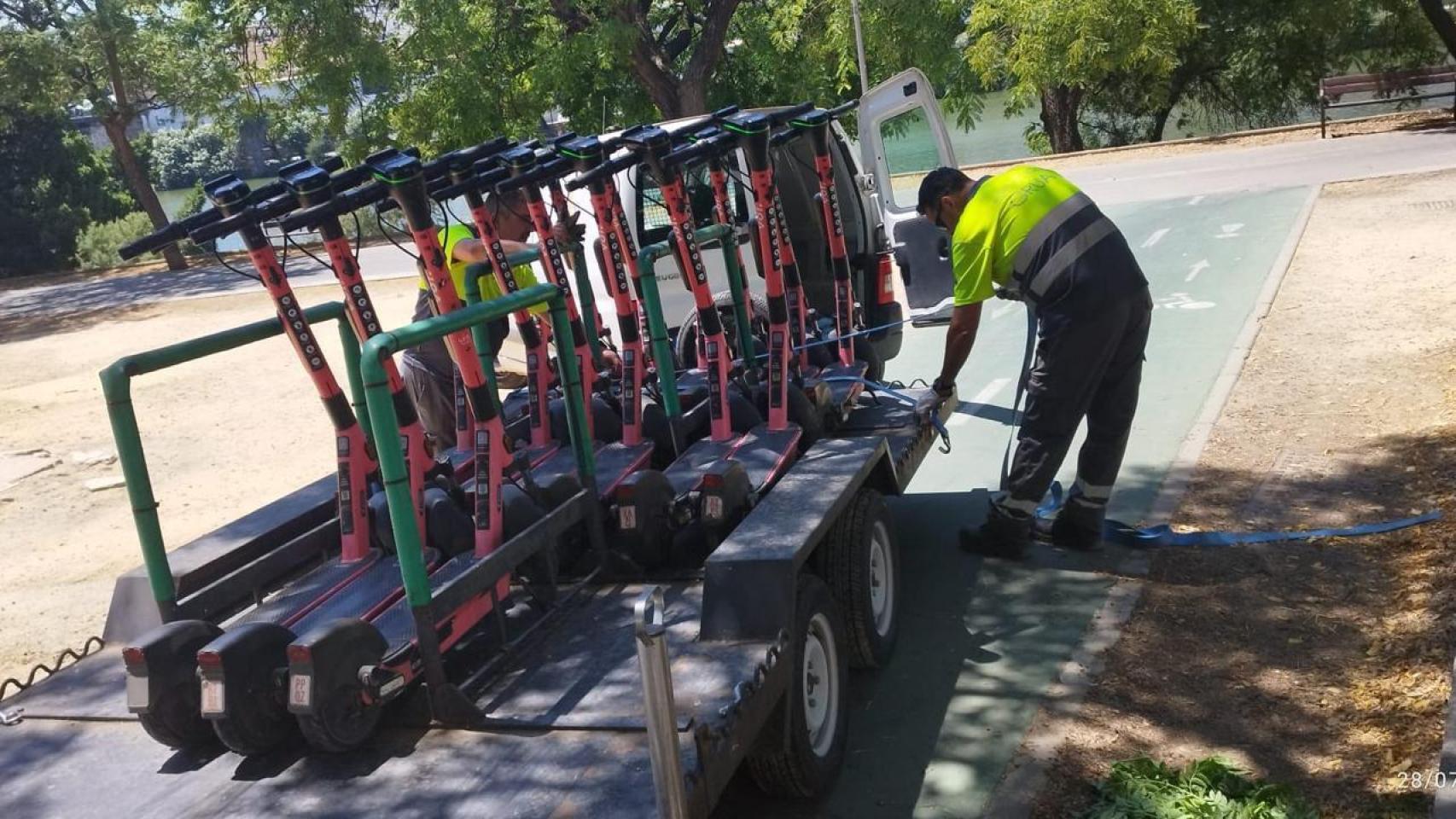 Operarios municipales retirando los patinetes eléctricos Voi.