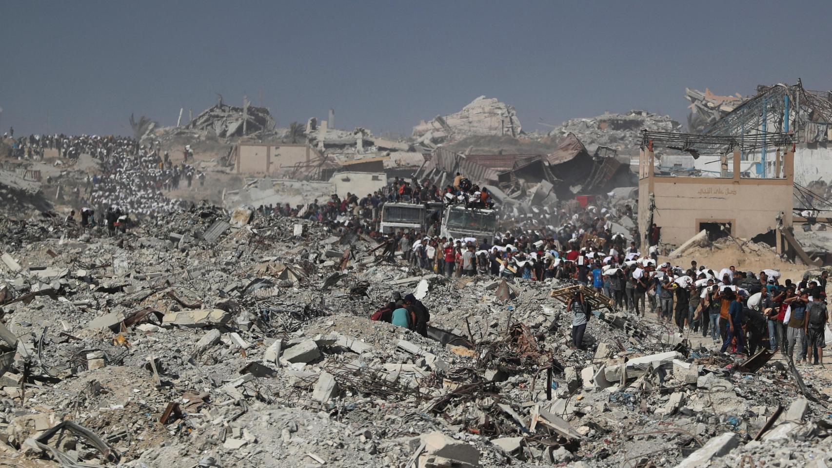 Palestinos transportan sacos de ayuda humanitaria en Gaza.