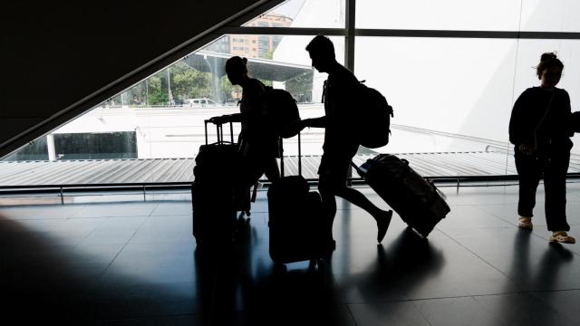 Imagen de archivo de dos viajeros con maletas.