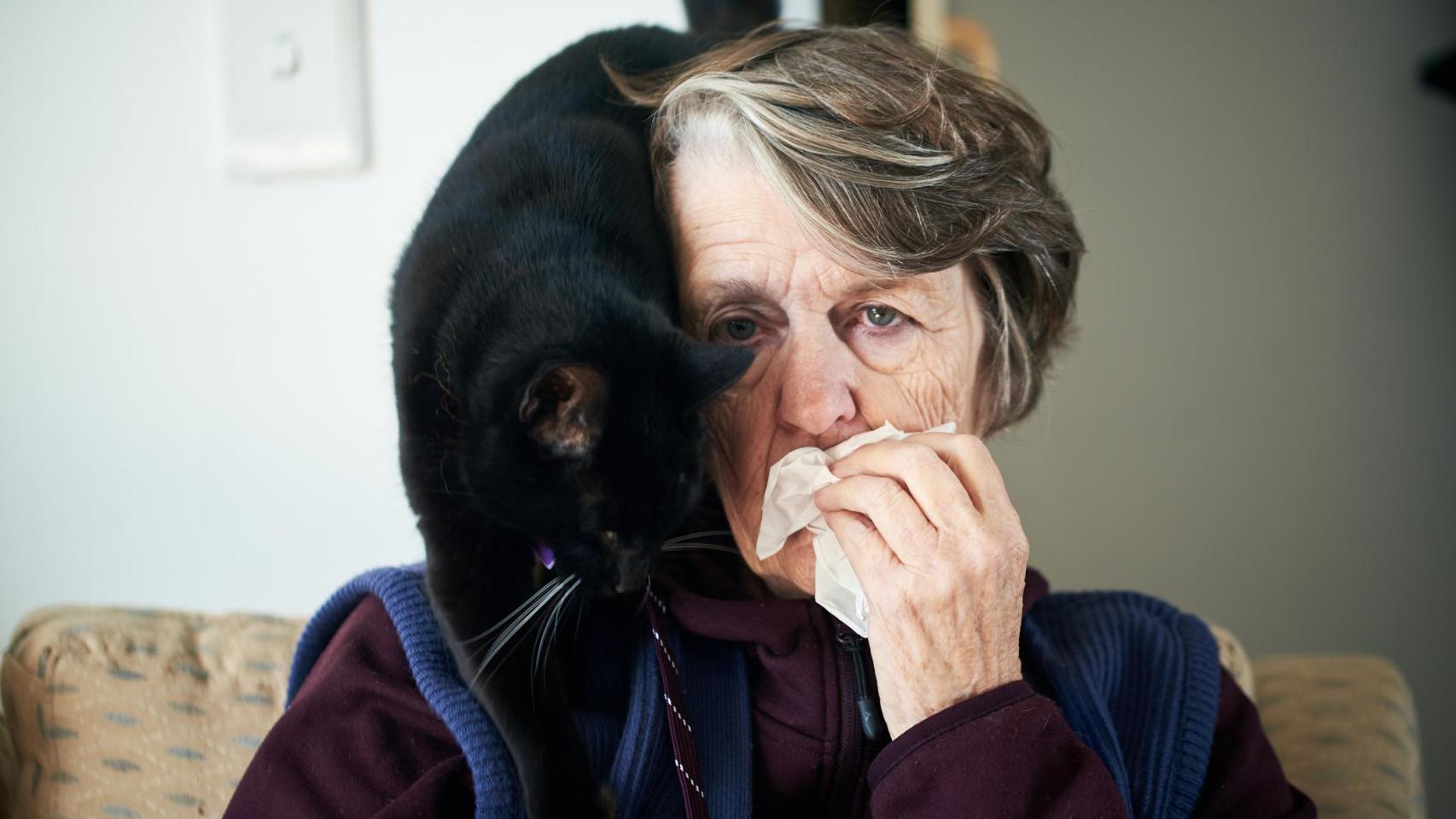 Una señora alérgica a los felinos, con un gato en la espalda.