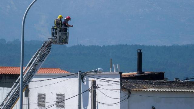 Varios bomberos sofocan el fuego, a 6 de agosto de 2025, en Rianxo, A Coruña, Galicia (España)