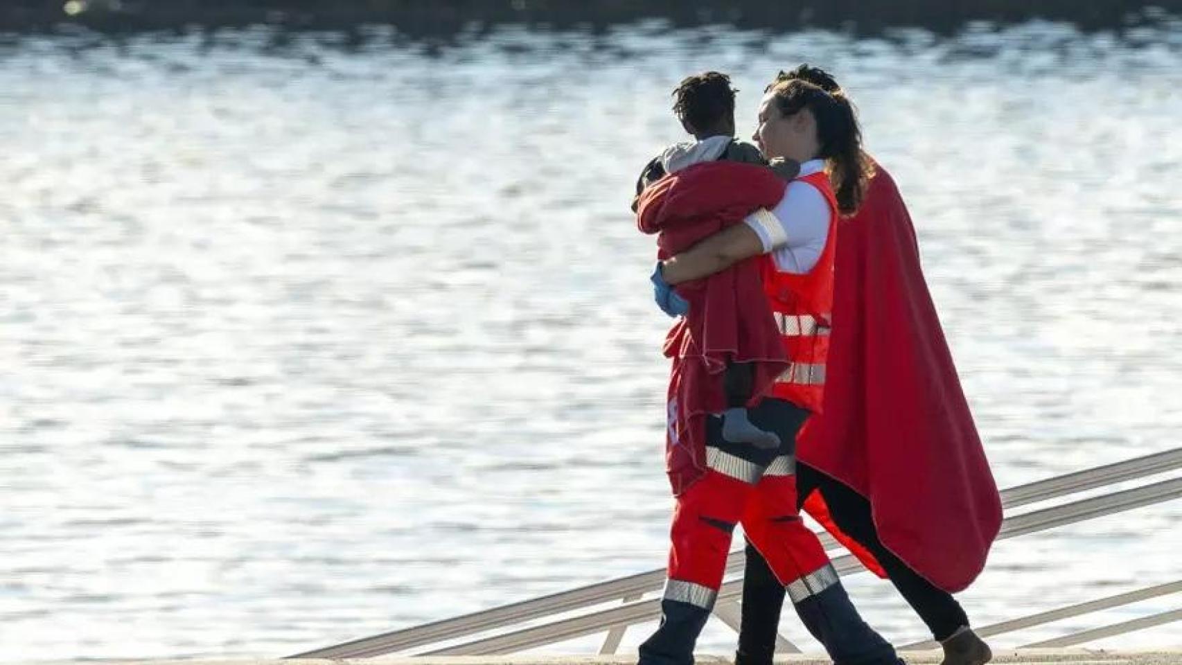 Trabajadora de la Cruz Roja lleva en brazos a un bebé tras la llegada de una patera a Arrecife.