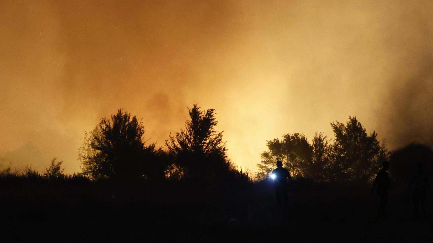 Un agente de Policía local evacúa a personas en el incendio que se ha declarado en la tarde de este lunes en la localidad madrileña de Tres Cantos
