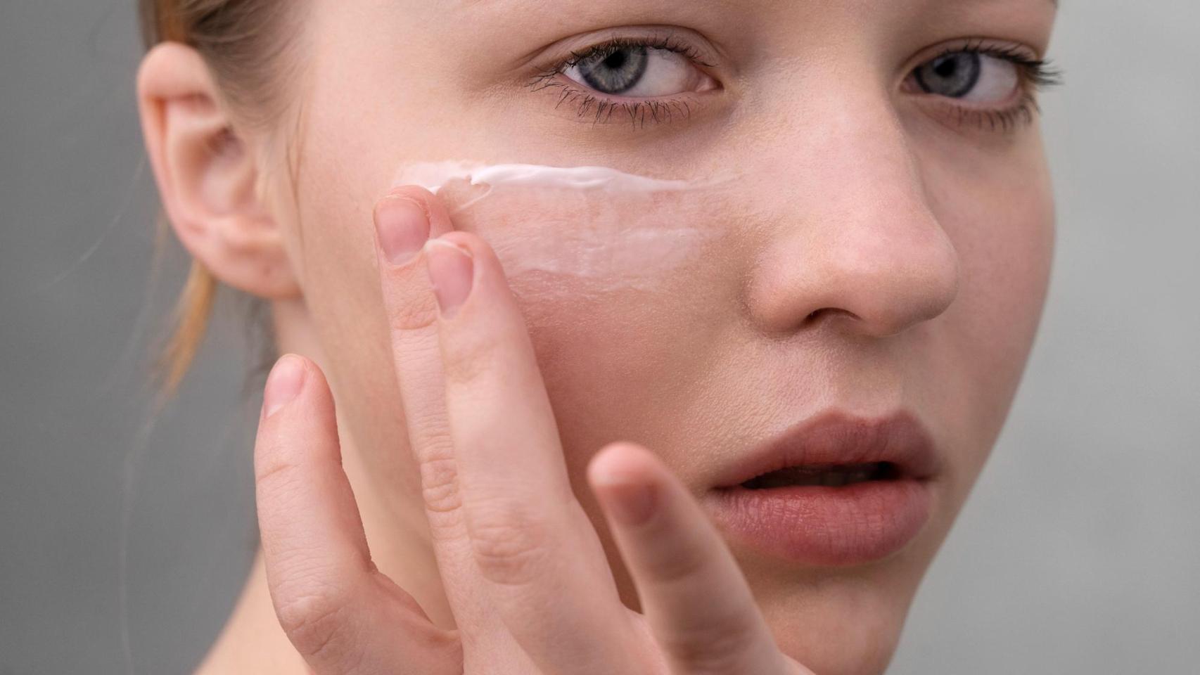 Mujer aplicándose crema en el rostro.