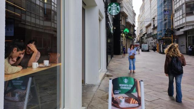 Acceso a la cafetería Starbucks de la calle Real de A Coruña, con productos para consumir en el local y para llevar.
