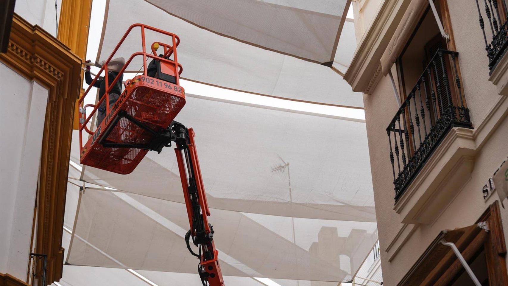 Un operario coloca toldos en la calle Sierpes.