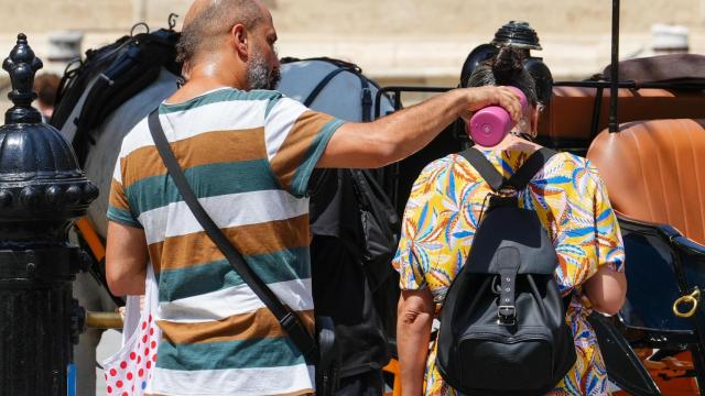 Peatones se refrescan con agua ante las altas temperaturas en Sevilla.