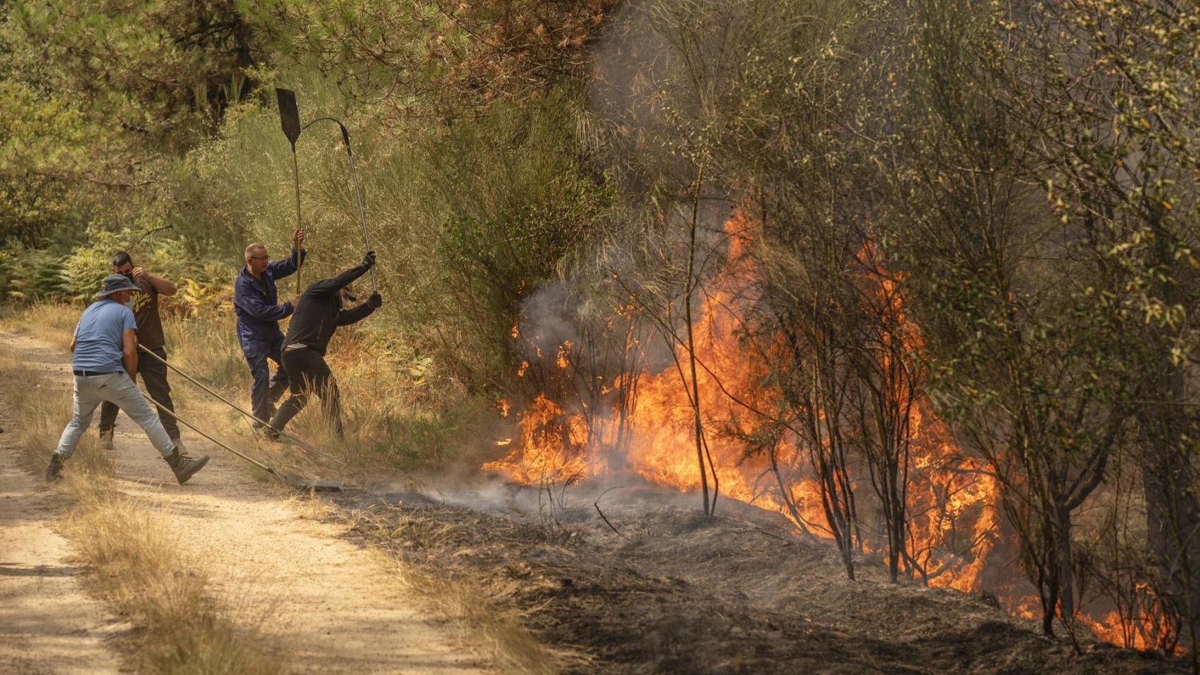 Unos vecinos trabajan en labores de extinción en un incendio forestal en la provincia de Ourense, este domingo.