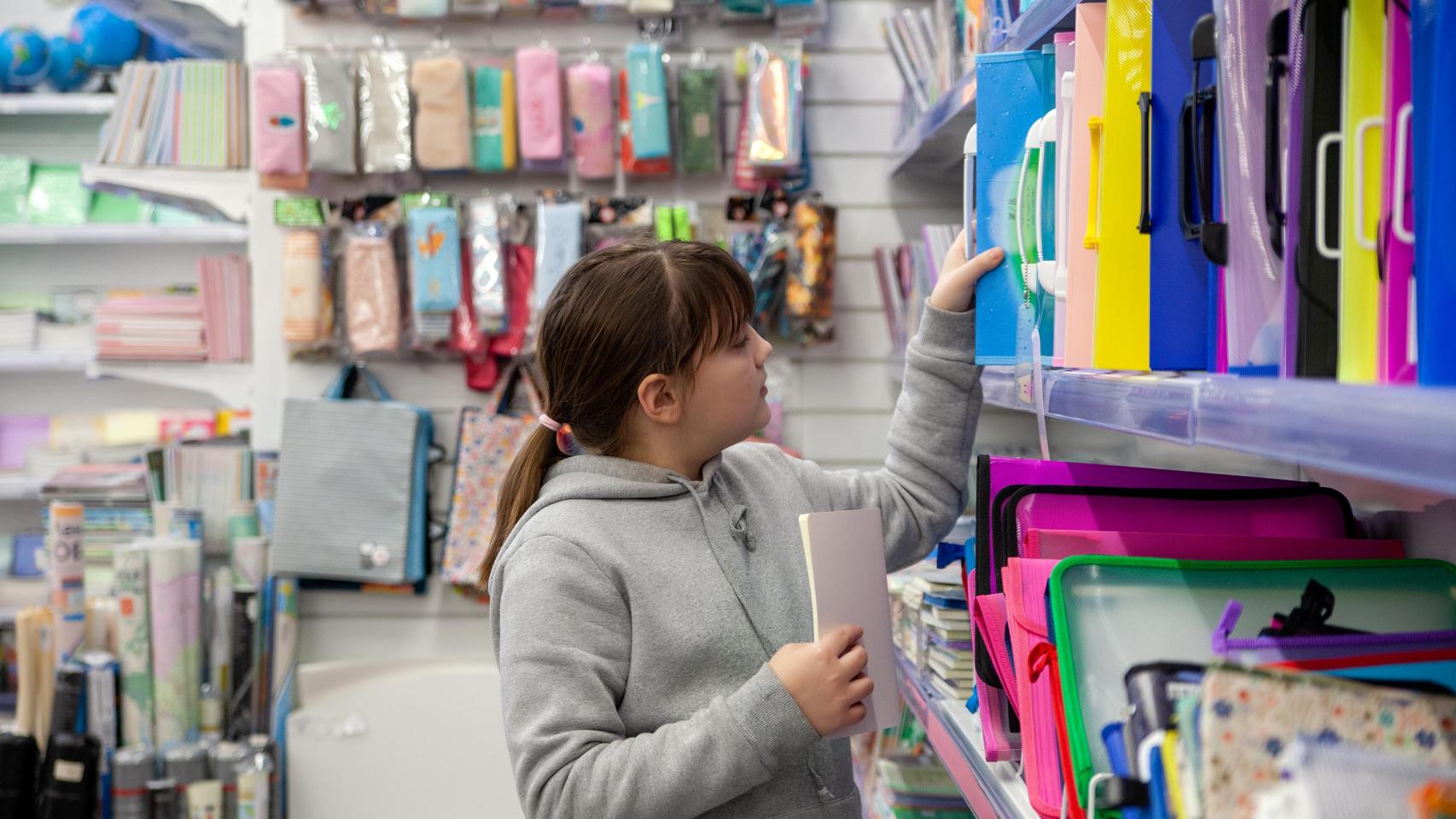 Niña eligiendo cuadernos en una papelería