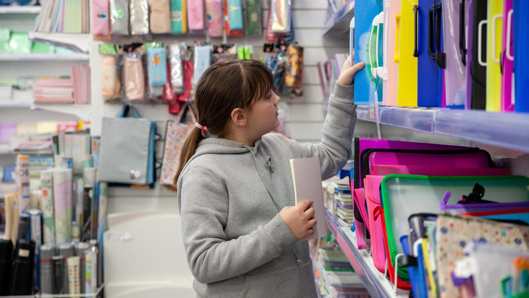 Niña eligiendo cuadernos en una papelería