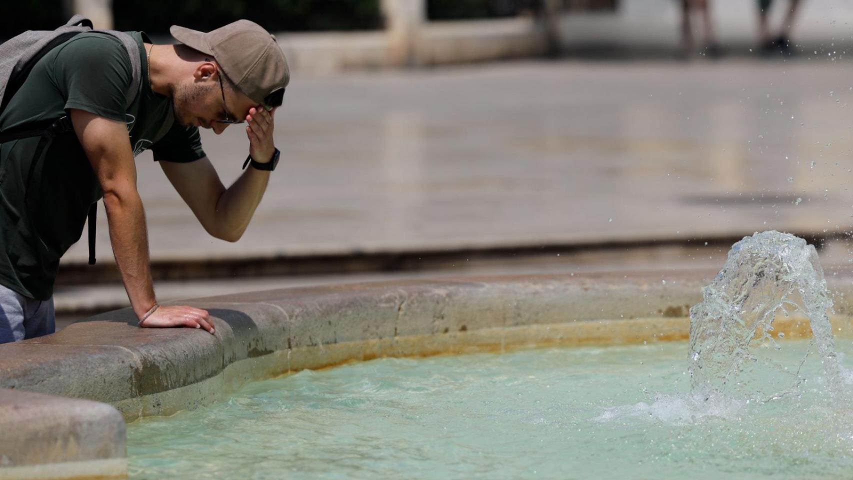 Un hombre echándose agua en una fuente en una imagen de archivo.