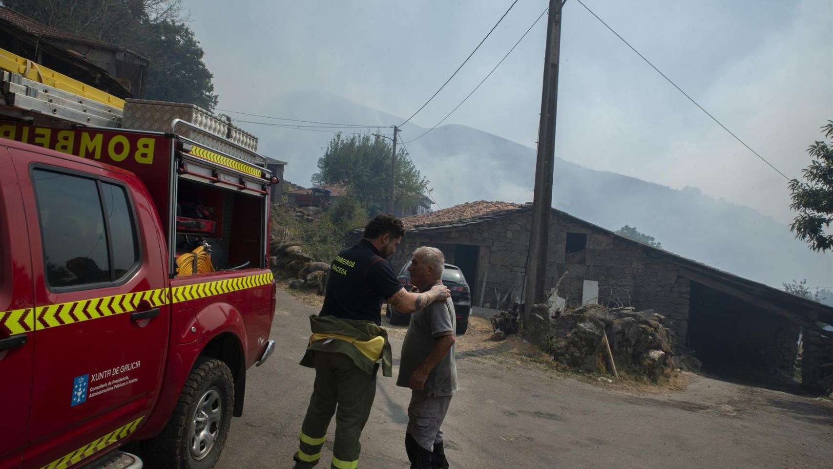 Un residente y un bombero después de la noche con el fuego alrededor de la aldea en Maceda, Ourense.