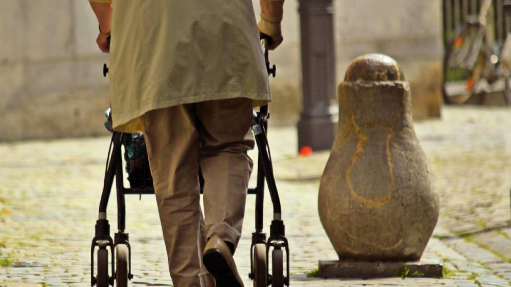 Una persona mayor camina por la calle con ayuda de un andador.