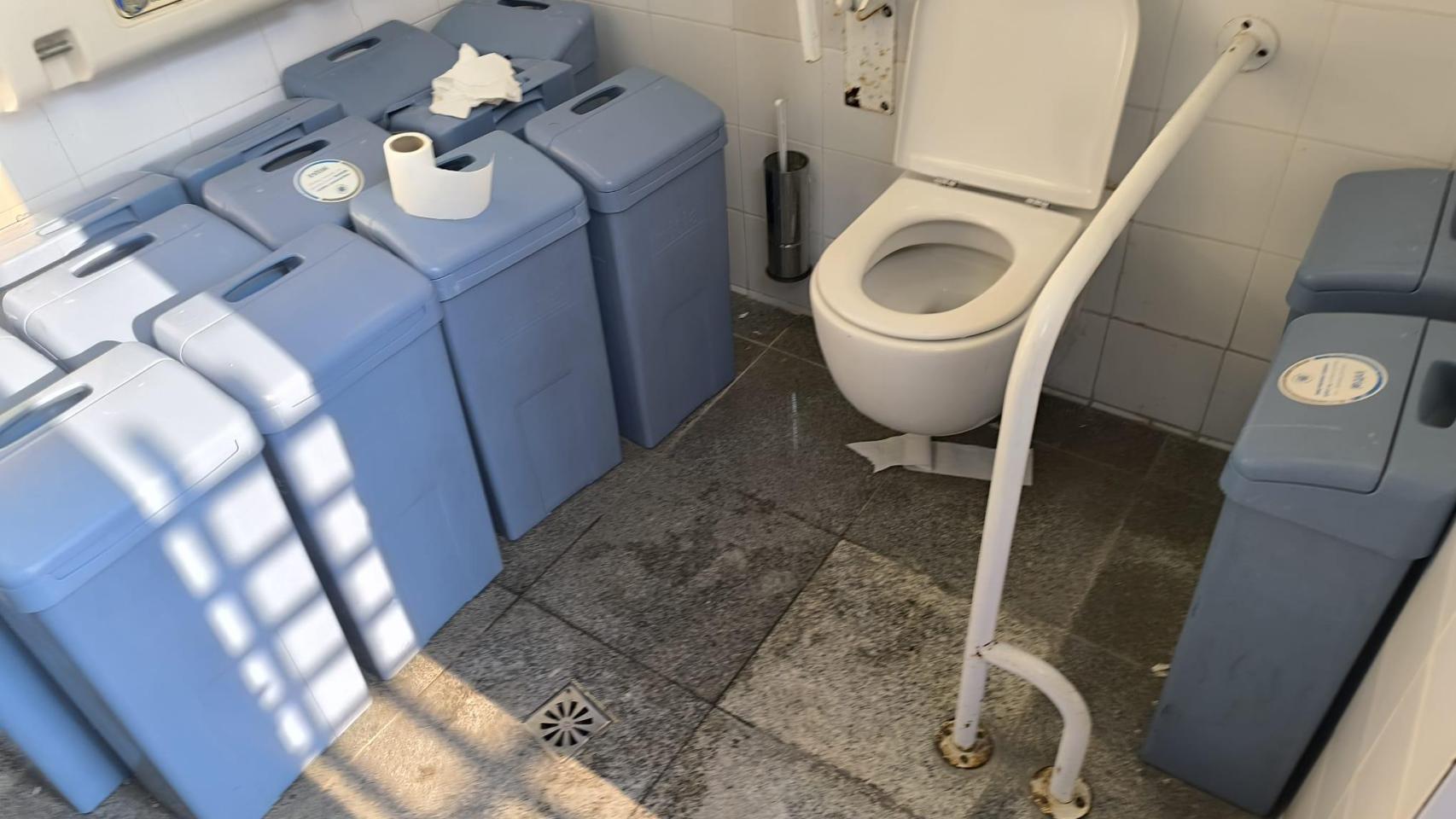 Estado de uno de los aseos con contenedores higiénicos acumulados y papel en el suelo, la mañana de este miércoles.