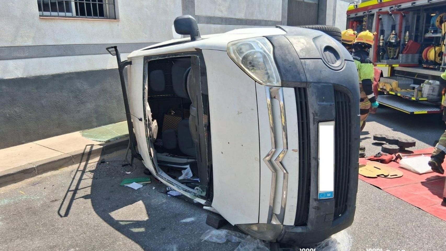 Efectivos de Bomberos y de la Policía Local intervienen tras el vuelco de un vehículo en Málaga.