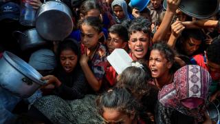 Palestinian children wait to receive some food from a soup kitchen in Khan Younis, southern Gaza Strip.