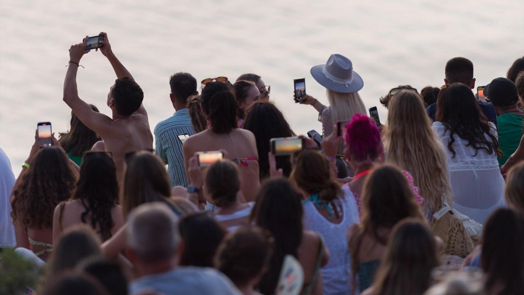 Turistas disfrutando del atardecer en la Cala d'Hort, en Ibiza, Baleares (España). Foto: Germán Lama / Europa Press