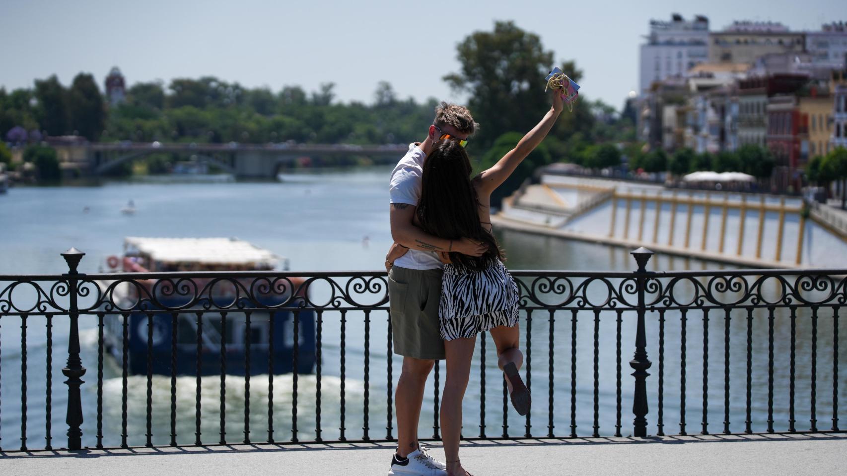 Dos personas se graban con el móvil en el Puente de Triana en Sevilla.