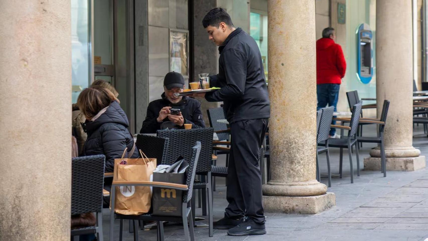Un camarero atendiendo las mesas de un bar.