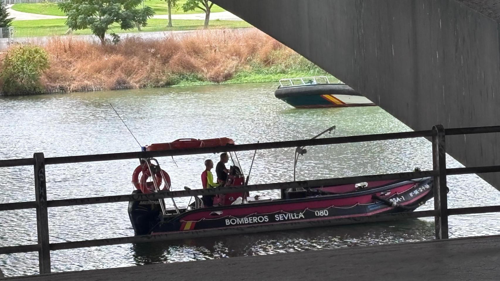 Una embarcación de los Bomberos busca a un hombre en los bajos del Puente del Cachorro de Sevilla.