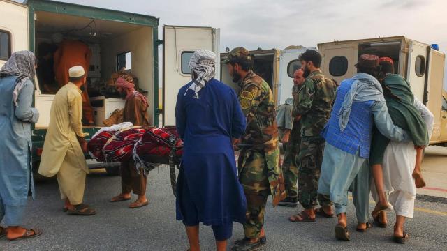 Soldados talibanes y grupos de civiles trasladan a ambulancias a víctimas del terremoto en el aeropuerto de Jalalabad.