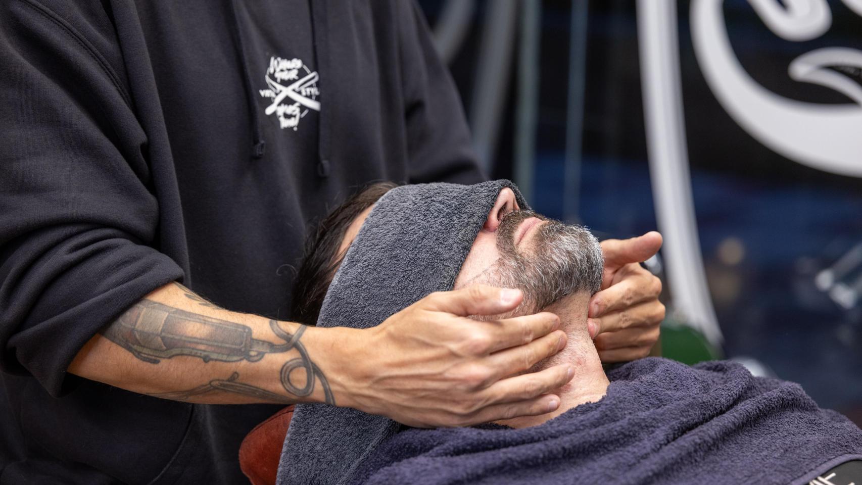 Un peluquero prepara a un cliente antes de arreglar su barba.