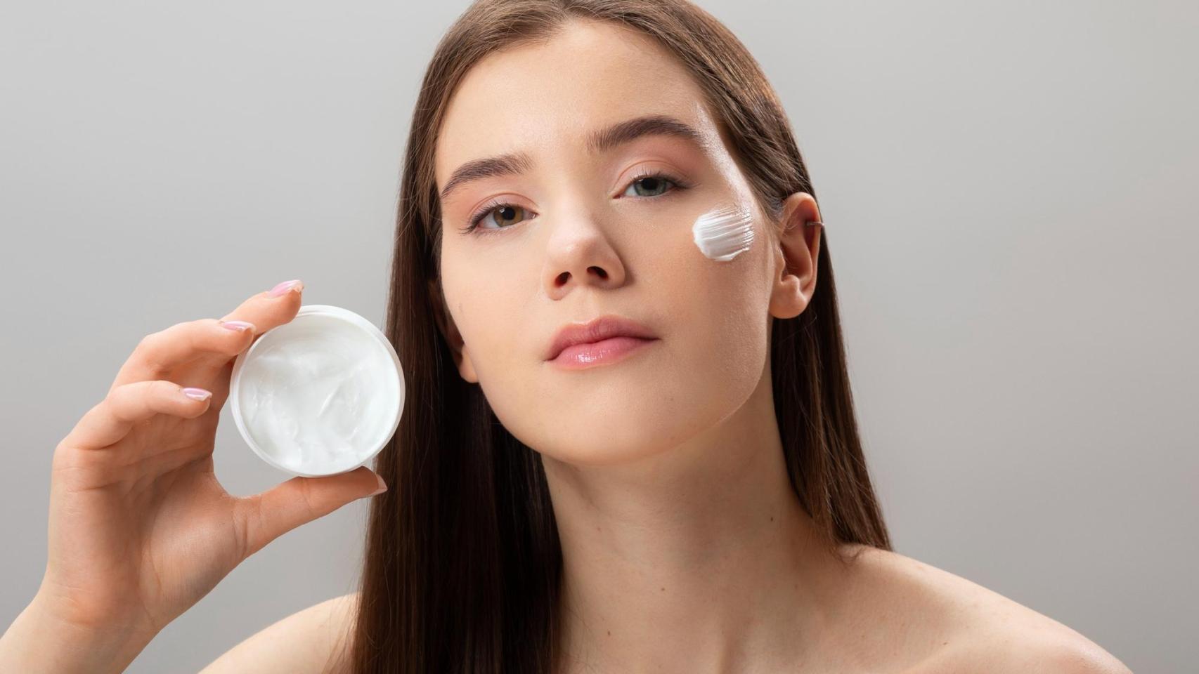 Mujer joven con un pote de crema en las manos.