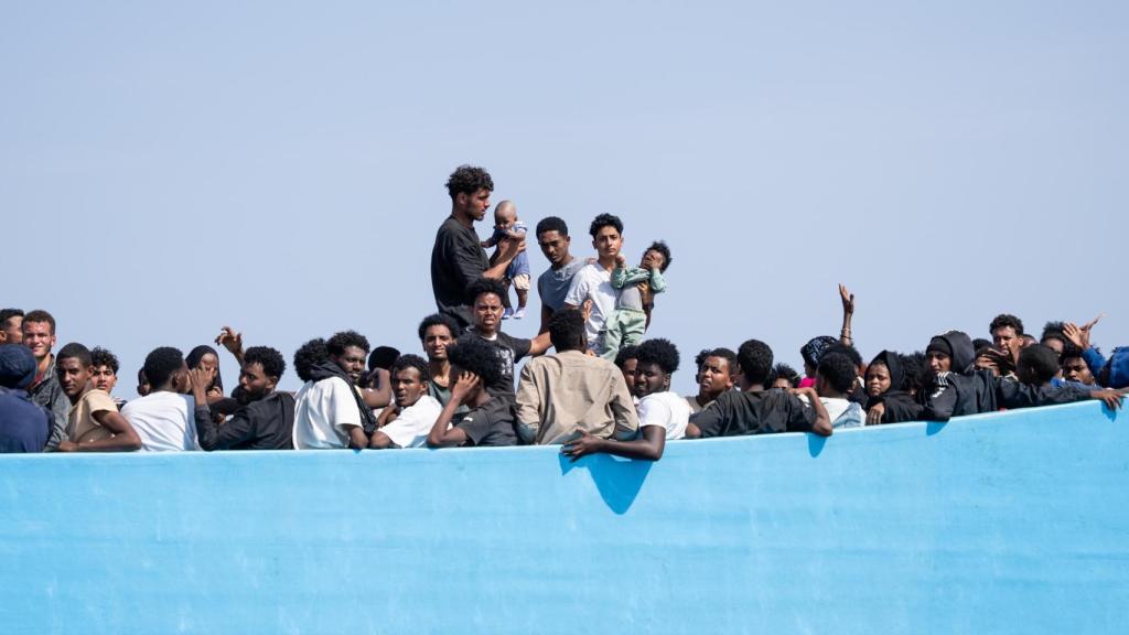 Migrantes muestran a dos bebés para que la lancha rápida de Open Arms les rescate.