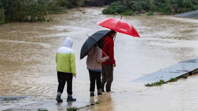 Varias personas intentan cruzar el cauce de la Rambla del Garruchal en Beniajan (Murcia)