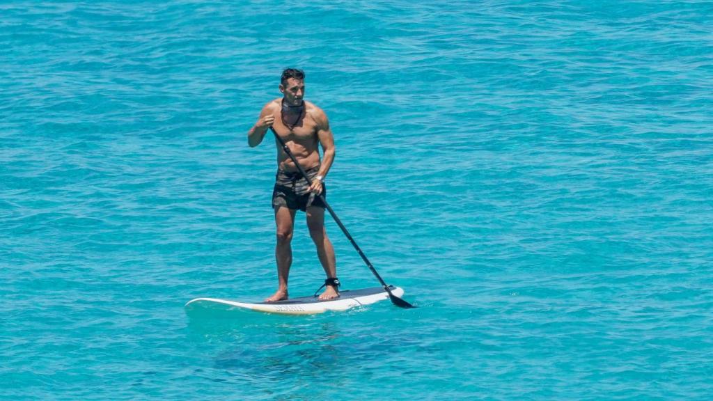 El presentador haciendo paddle surf en el mar.