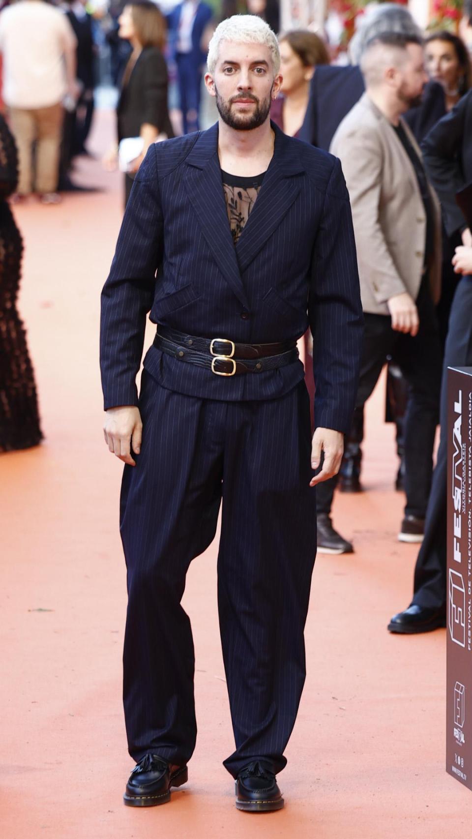 David Broncano con un traje de línea diplomático, top de encaje y doble cinturón.
