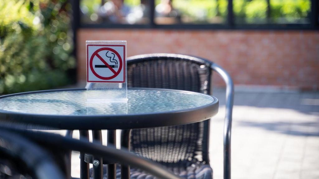 Una mesa en una terraza con el letrero de 'Prohibido fumar'.