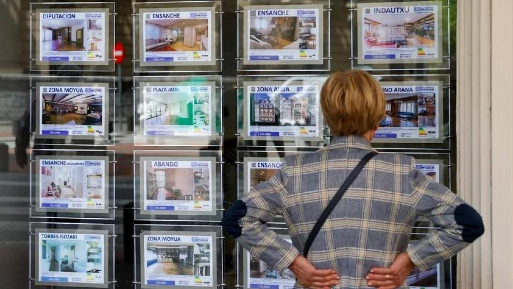 Una mujer mira la oferta de viviendas en una inmobiliaria en Bilbao.