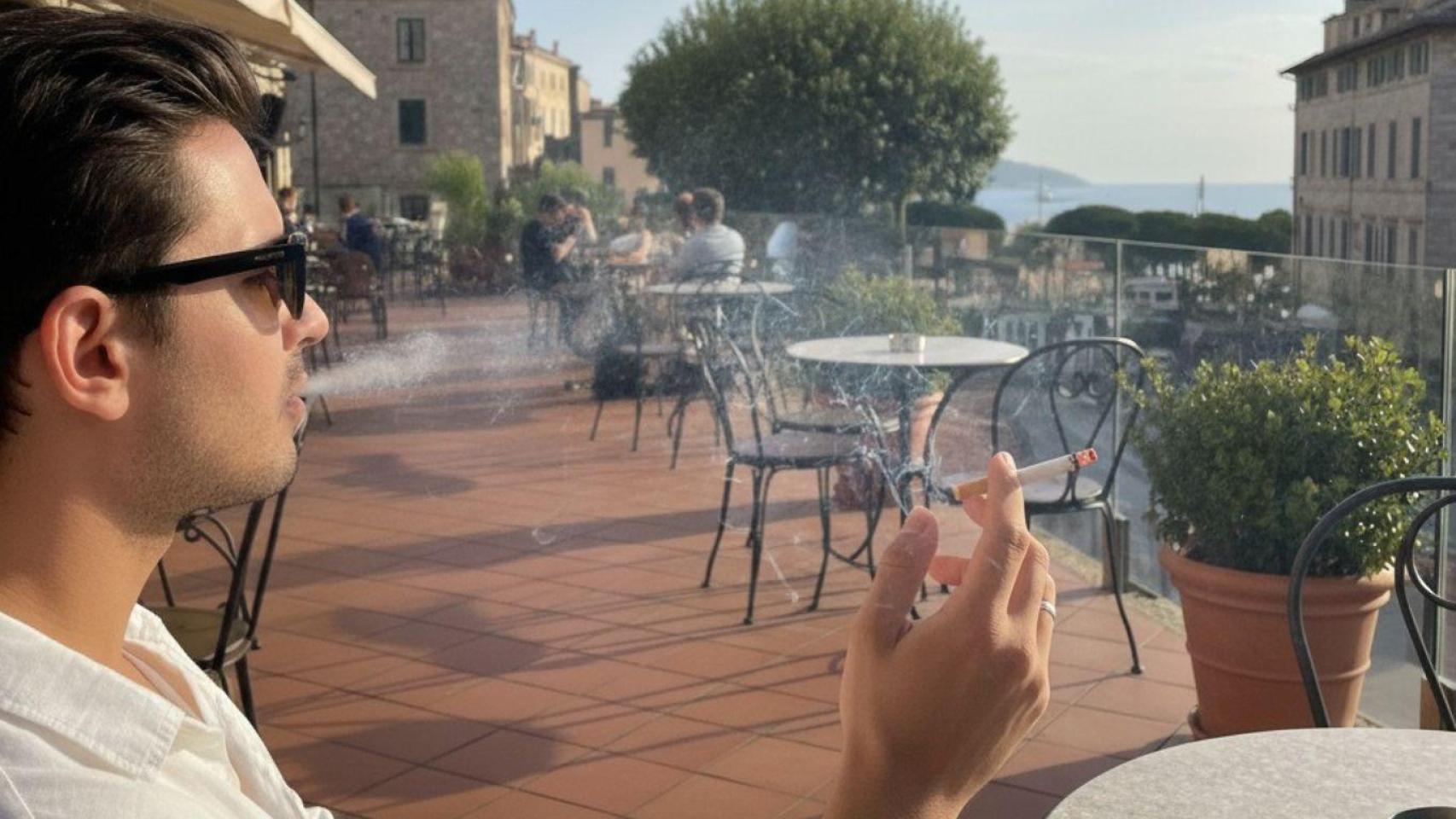 Un hombre fumando en una terraza.