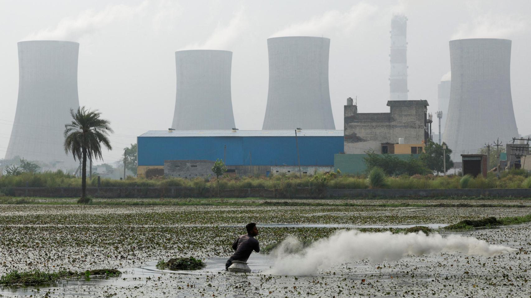 Un hombre pesca frente a una explotación de combustibles fósiles.