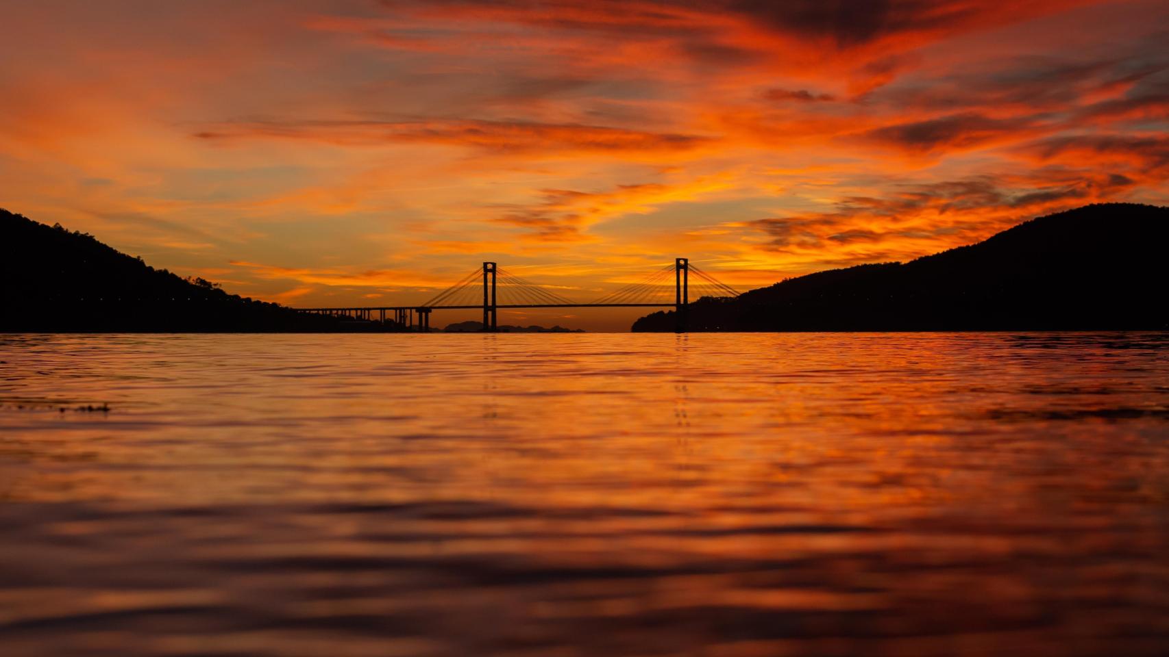 Vista del puente y el estuario de Vigo desde la playa de Cesantes en una impresionante puesta de sol