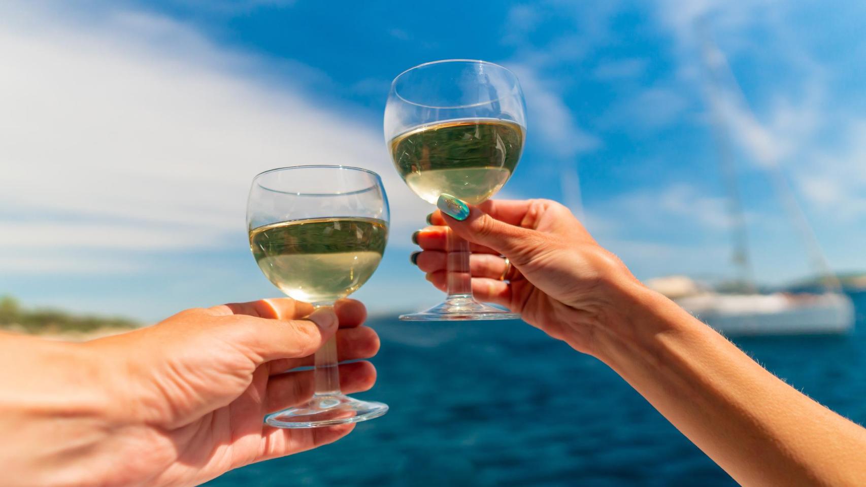 Dos copas de vino blanco frente al mar.