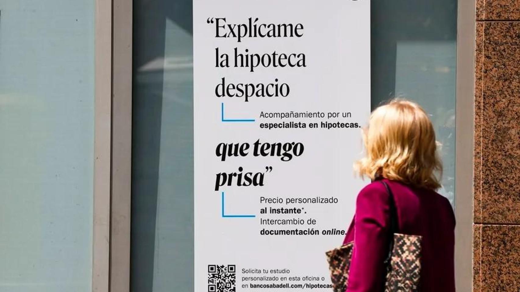 Una mujer ante un cartel bancario sobre las hipotecas.