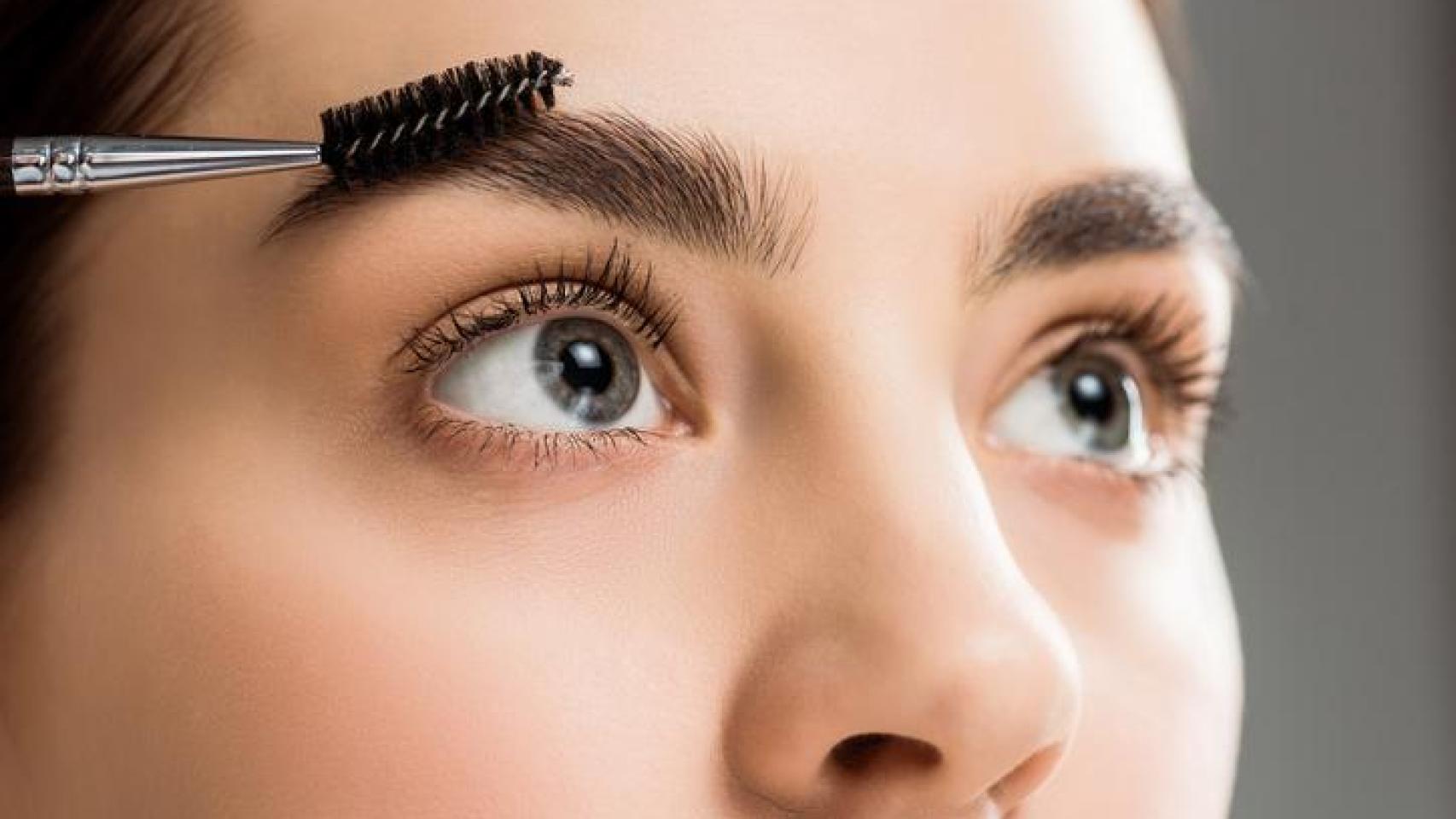 Mujer peinándose las cejas.