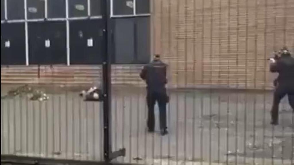 Dos agentes apuntan al sospechoso del ataque, herido en el suelo, antes de disparar.