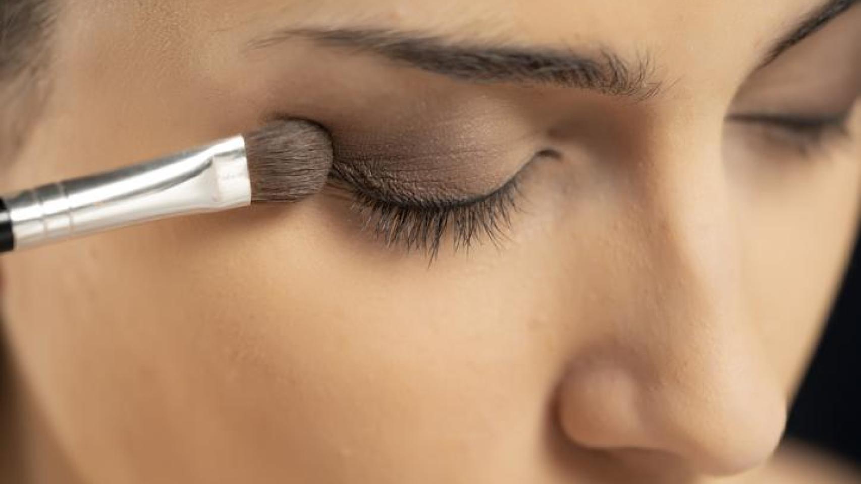 Mujer maquillándose los ojos en ahumado.