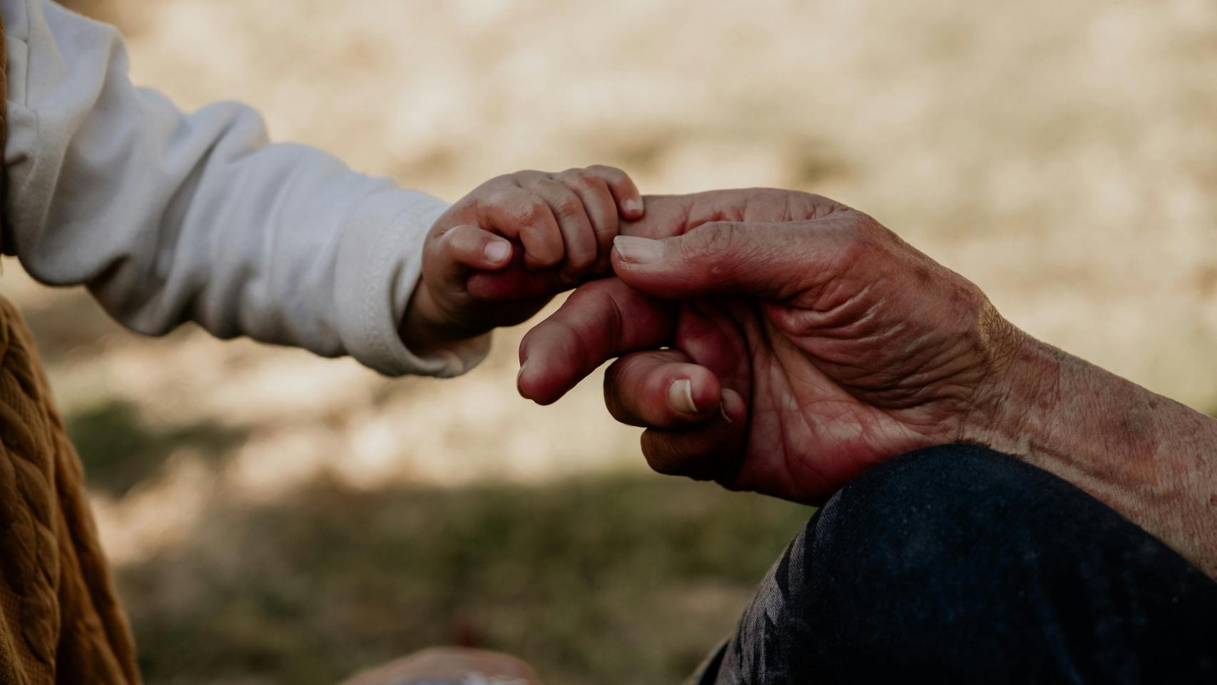Las manos de una señora mayor junto a las de una niña, en una imagen de archivo.