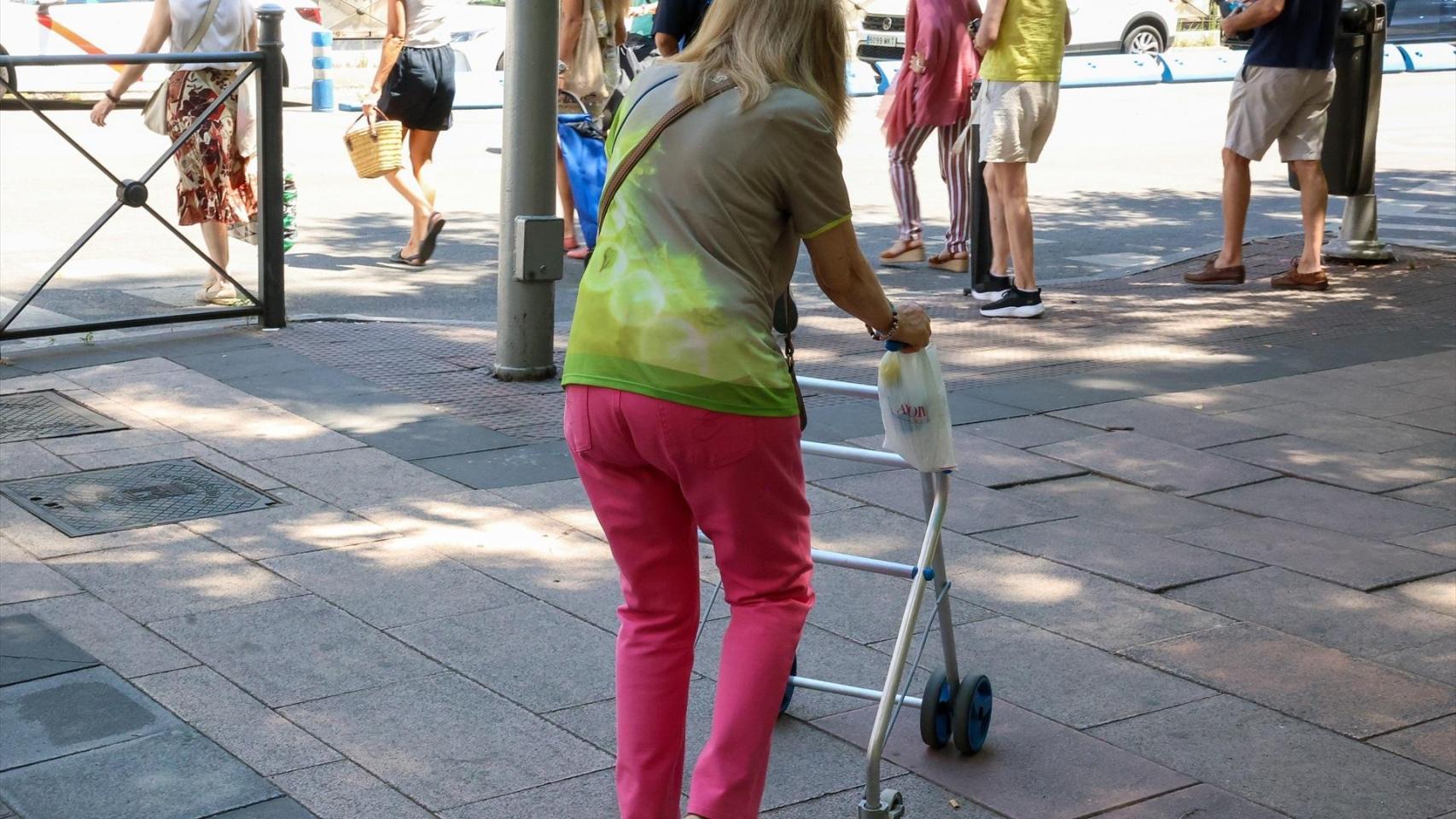 Persona mayor caminando por la calle ayudada por un andador. EP