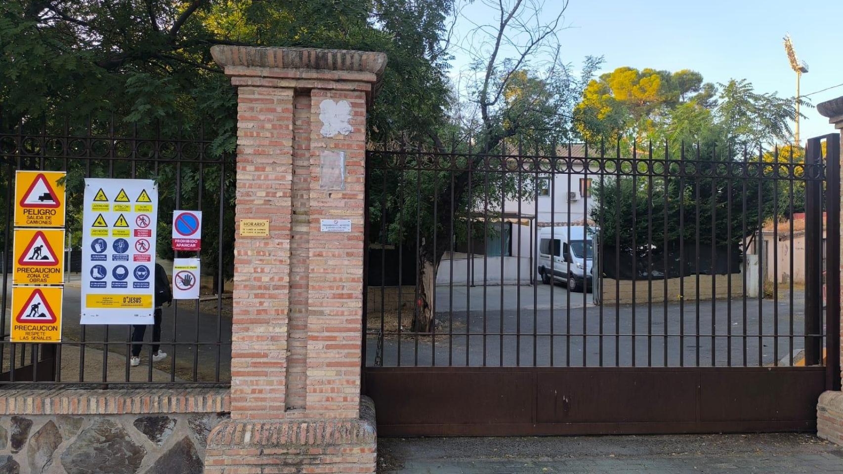 La valla de acceso a los antiguos chalés de la Escuela de Gimnasia está cerrada por obras. Al fondo el patio del centro de la Asociación de Familiares de Alzheimer (AFA) de Toledo.