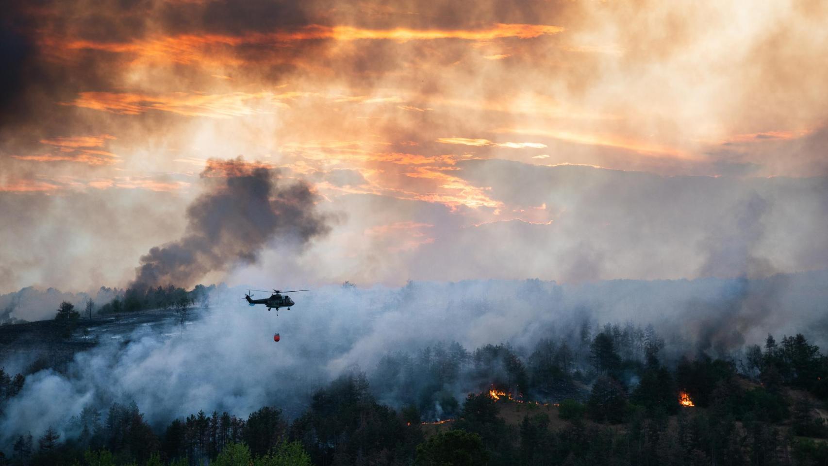 Un helicóptero de emergencias trabaja sobre un incendio forestal.